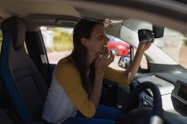 Donna che guarda lo specchio retrovisore in un'auto — Foto stock