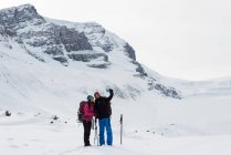 Coppia scattare selfie con cellulare su una montagna innevata durante l'inverno — Foto stock