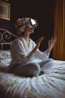 Жінка використовує гарнітуру віртуальної реальності в спальні вдома — стокове фото