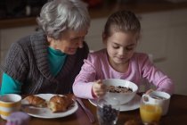 Großmutter und Enkelin frühstücken zu Hause in der Küche — Stockfoto