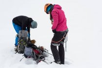Paar trägt im Winter Gurtzeug auf einem schneebedeckten Berg — Stockfoto