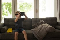 Garçon utilisant casque de réalité virtuelle dans le salon à la maison — Photo de stock