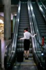 Woman standing on escalator with luggage at airport — Stock Photo