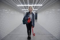 Молодая женщина стоит со скейтбордом в метро — стоковое фото