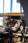 Женщина плотник с помощью вертикальной буровой машины в мастерской — стоковое фото