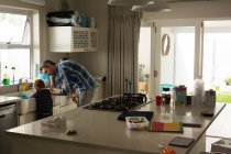 Padre e hijo fregadero de limpieza en la cocina en casa - foto de stock