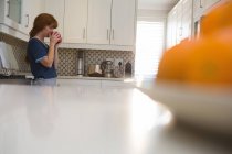 Женщина пьет кофе на кухне дома — стоковое фото