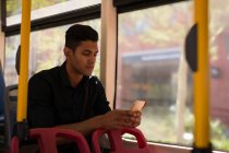 Jovem empresário usando telefone celular enquanto viaja em ônibus — Fotografia de Stock