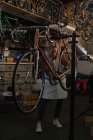 Mechanikerin begutachtet Fahrrad in Werkstatt — Stockfoto