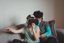 Бабушка и внучка используют гарнитуру виртуальной реальности в гостиной дома — стоковое фото