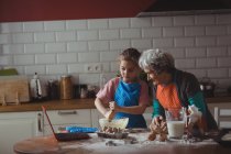 Бабушка и внучка готовят дома печенье на кухне. — стоковое фото