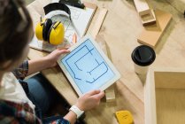 Tischlerin schaut sich Plan auf digitalem Tablet in Werkstatt an — Stockfoto