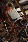 Женщина-механик осматривает велосипед в мастерской — стоковое фото
