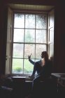Жінка, беручи selfie з мобільного телефону біля вікна будинку — стокове фото