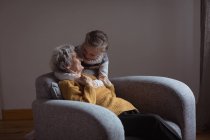 Enkelin umarmt Großmutter im heimischen Wohnzimmer — Stockfoto