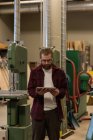 Carpinteiro masculino usando comprimido digital na oficina — Fotografia de Stock