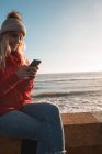 Jovem mulher usando telefone celular na praia — Fotografia de Stock