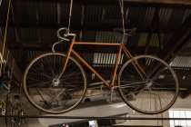 Racing bicycle hanging in workshop — Stock Photo