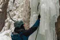 Masculino alpinista escalando montanha de gelo durante o inverno — Fotografia de Stock