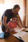 Father helping her daughter in her homework at home — Stock Photo