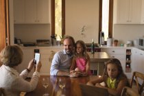 Мама фотографирует отца и дочь с мобильного телефона дома — стоковое фото