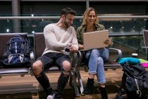 Пара с ноутбуком в зоне ожидания в аэропорту — стоковое фото