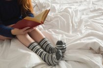 Donna che legge un libro in camera da letto a casa — Foto stock