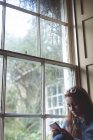 Frau benutzte Handy in der Nähe von Fenster zu Hause — Stockfoto