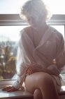Nachdenkliche Frau sitzt zu Hause am Fenster — Stockfoto