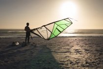 Чоловічий серфер готує повітряний змій на пляжі в сутінках — стокове фото
