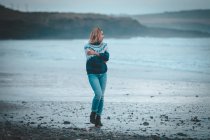 Mujer pensativa caminando en una playa - foto de stock