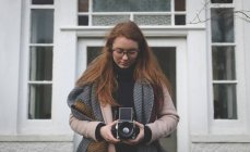 Жінка фотографується з старовинною камерою на задньому дворі свого будинку — стокове фото