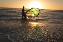 Male surfer surfing with surfboard and kite at beach — Stock Photo