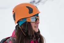 Продуманий жіночий альпініст стоячи з шолом і сонцезахисні окуляри на засніжених регіон — стокове фото