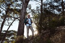 Escursionista anziano in piedi con zaino nella foresta in campagna — Foto stock