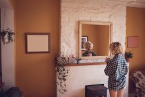 Mulher olhando no espelho enquanto toma café em casa — Fotografia de Stock