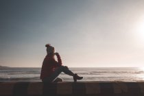 Задумчивая женщина сидит рядом с пляжем — стоковое фото