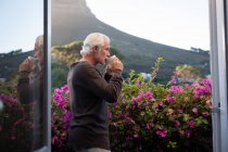 Активний старший чоловік має каву на балконі — стокове фото