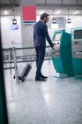 Empresário usando a máquina de bilhetes de avião no aeroporto — Fotografia de Stock