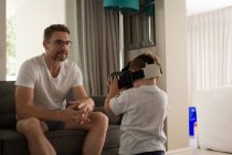 Father looking at his son using virtual reality headset in living room at home — Stock Photo
