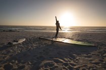 Surfeur masculin debout avec cerf-volant et planche de surf sur la plage au crépuscule — Photo de stock