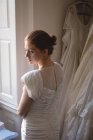 Young bride in wedding dress standing near window at boutique — Stock Photo