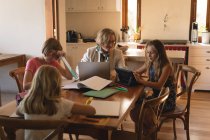 Madre che usa il computer portatile mentre i bambini dosano i loro compiti a casa — Foto stock