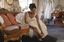 Mixed race bride in wedding dress wearing high heels at boutique — Stock Photo