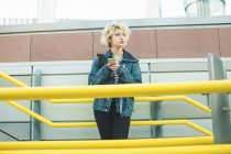 Молода жінка використовує мобільний телефон біля сходів — стокове фото