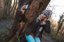 Молода жінка бере селфі з мобільним телефоном у лісі — стокове фото