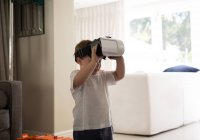 Мальчик использует гарнитуру виртуальной реальности в гостиной дома — стоковое фото