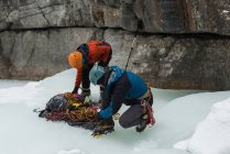 Scalatore maschio che indossa ramponi vicino alla montagna rocciosa durante l'inverno — Foto stock