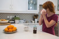 Женщина пьет черный кофе на кухне дома — стоковое фото