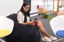 Молодая женщина исполнительная с помощью мобильного телефона в офисе — стоковое фото